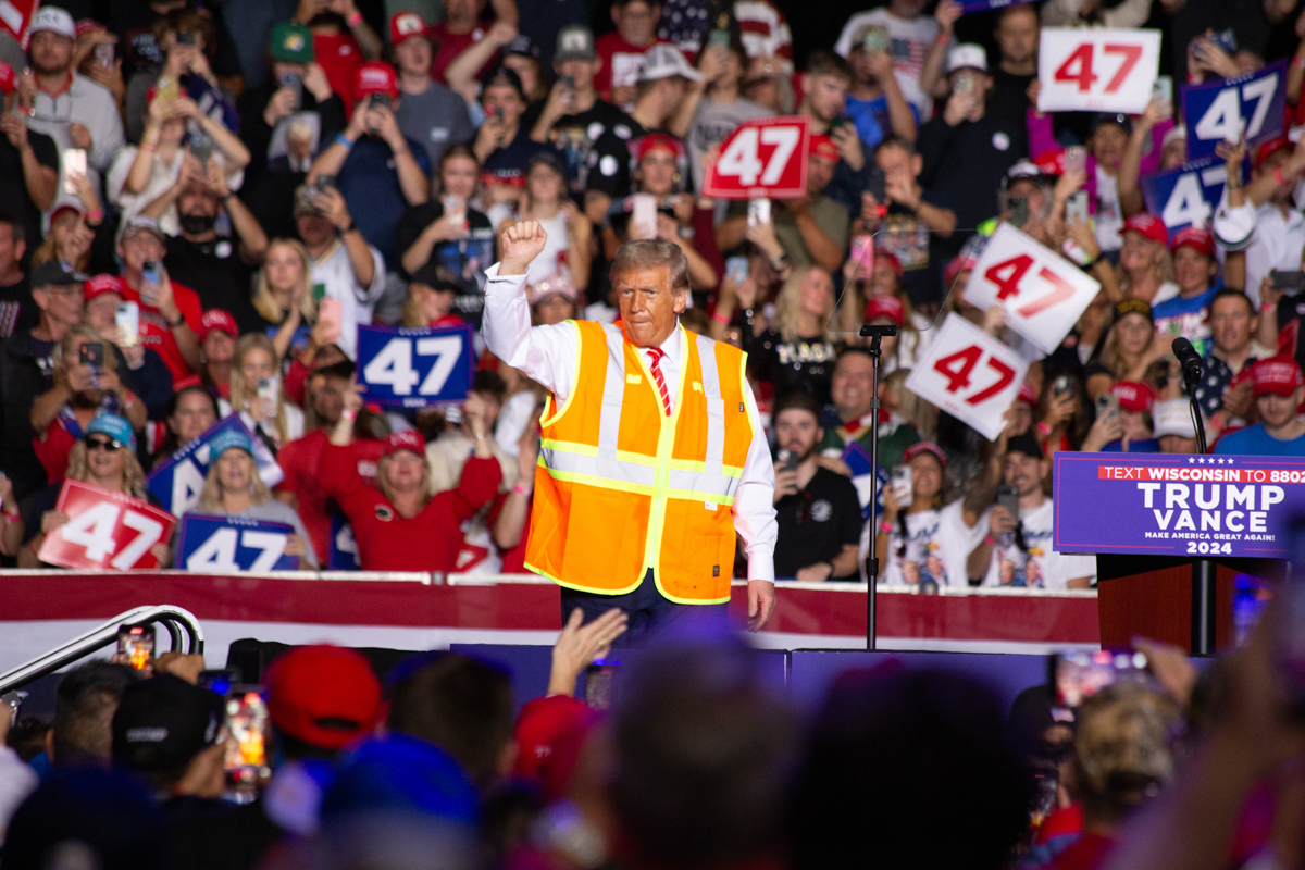 Donald Trump on stage with an orange high-visibility vest at the Green Bay rally