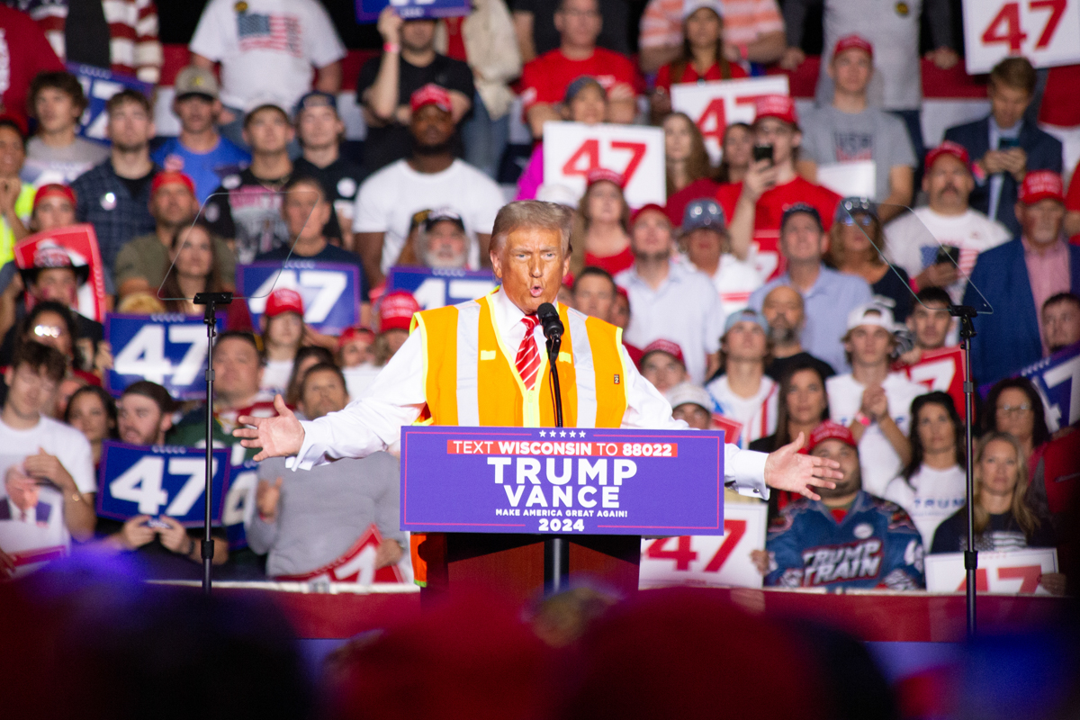 Donald Trump on stage with an orange high-visibility vest at the Green Bay rally