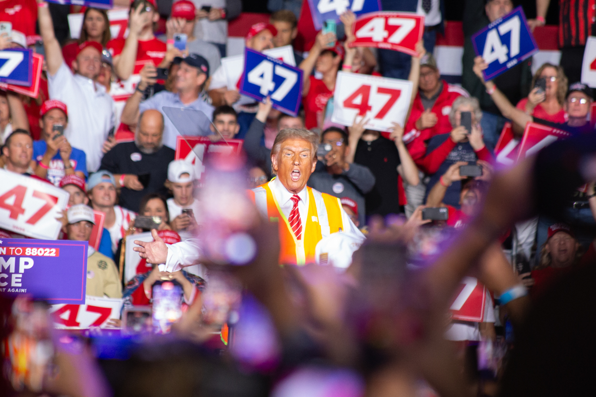 Donald Trump on stage with an orange high-visibility vest at the Green Bay rally