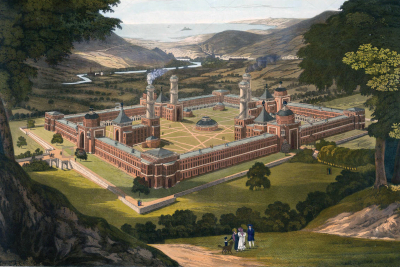 Aerial view of a large, ornate building complex surrounded by landscaped grounds and hills in the background.
