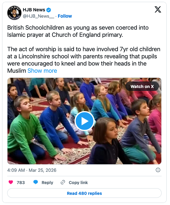 A group of schoolchildren sitting on the floor, participating in a prayer session in a classroom setting, with some children kneeling and bowing their heads.