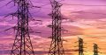 Four high voltage electric tower pylons contrasting against a brightly glowing evening sunset.